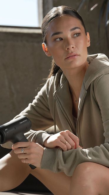 Woman holding a massage gun.