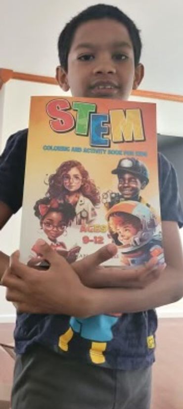 A young Brown Boy with a cartoon shirt is holding up our book.