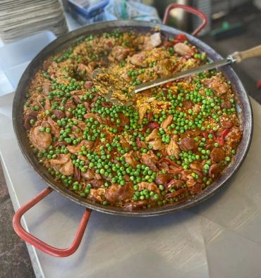 Large pan of paella with peas, shrimp, and sausage.