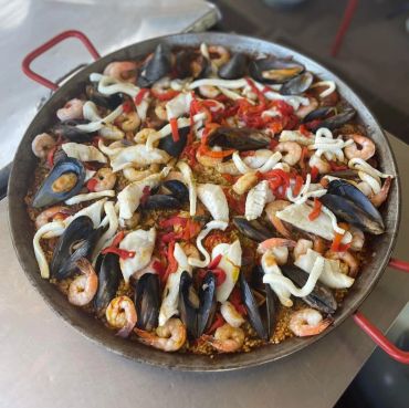Seafood paella served in a pan with shrimp, mussels, and squid.