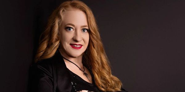 Portrait of a woman with red hair and bright makeup.