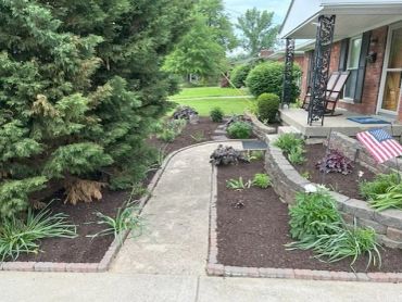 Well-maintained garden path with plants and mulch.