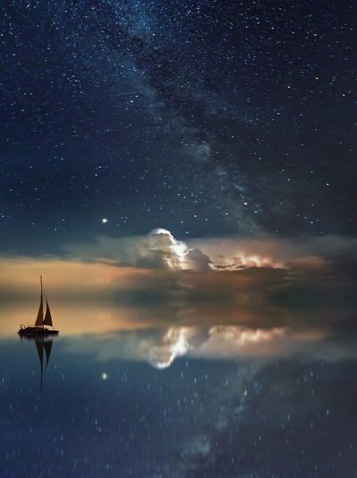 Sailboat under starry night sky reflecting on calm water.