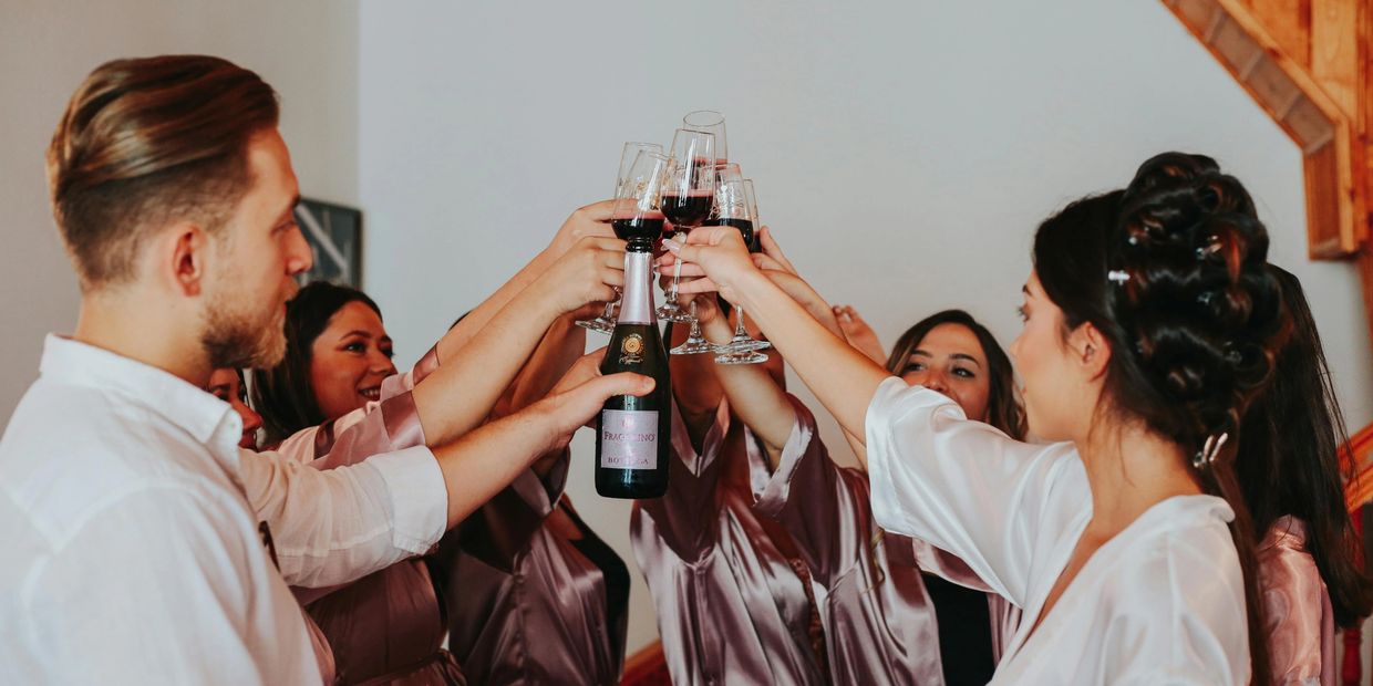 A bride and her bridesmaids in their robes, share a toast to the upcoming celebration.