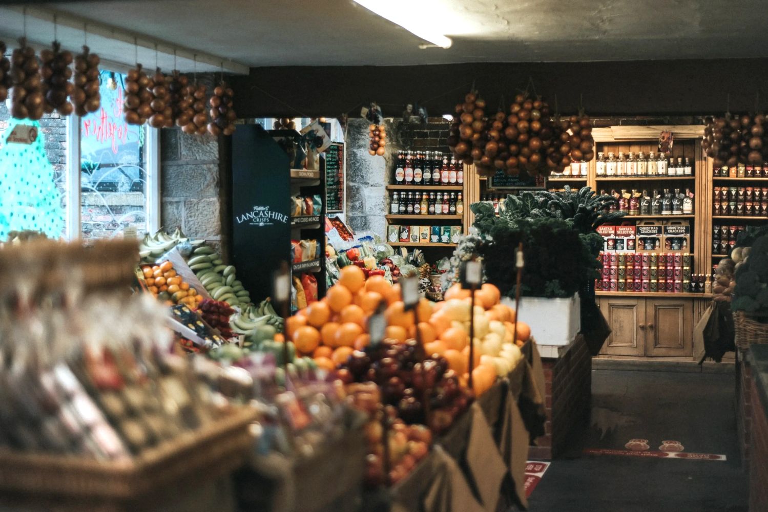 Inside a rustic grocery store with hanging onions and fresh produce.