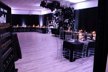 Elegant black-themed party setup with transparent chairs and candlelit tables.