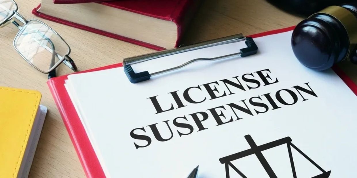 Document titled 'License Suspension' on a clipboard with legal items nearby.