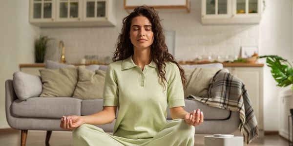A woman meditates in a room, finding inner peace and tranquility amid a holistic wellness journey.