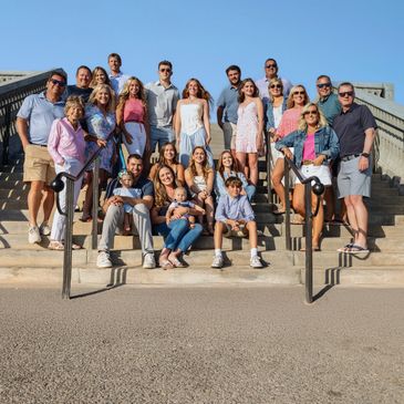 Large family posing together on outdoor steps under clear blue sky.