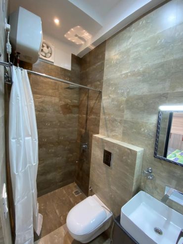 Compact modern bathroom with shower, toilet, and sink.