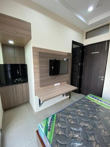 Modern bedroom corner with mounted TV and wardrobe.