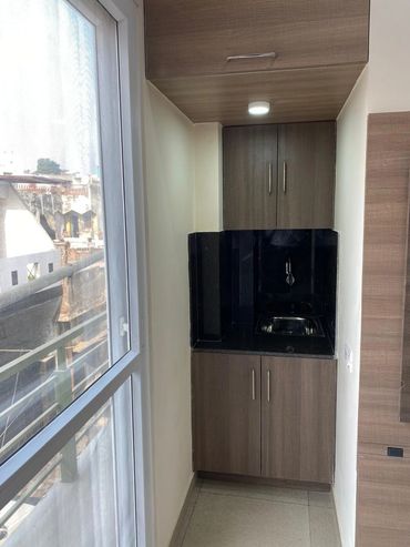 Compact kitchenette area with sink and cabinets near a window.