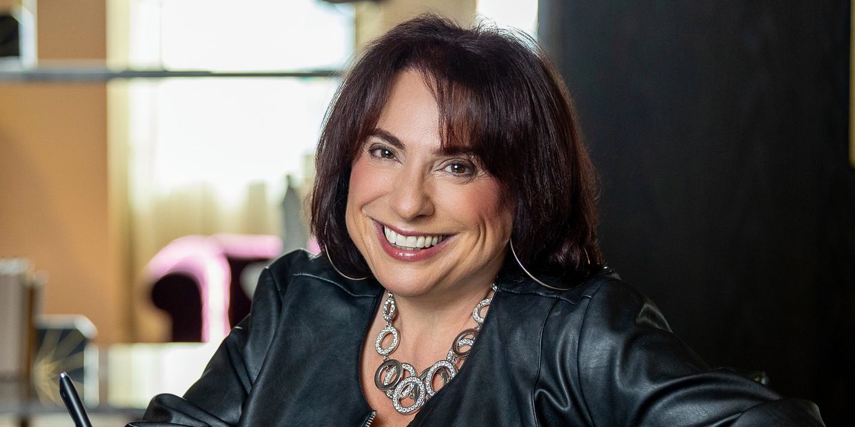 Smiling woman writing in a notebook at a desk.