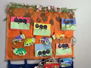 Colorful insect crafts displayed on an orange board with floral decorations.