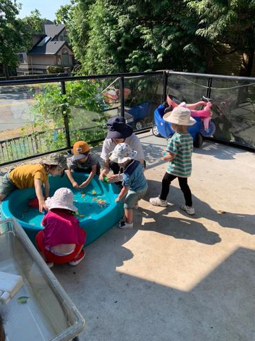 Children playing with water toys in a small pool on a sunny patio.