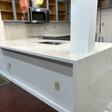 Modern kitchen island with white marble countertop and built-in sink.