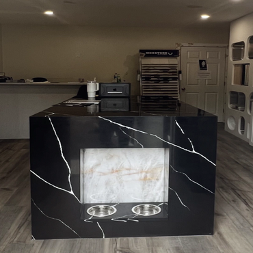 Modern showroom with marble island and wooden flooring.