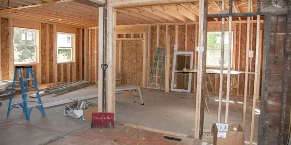 Interior of a house under construction with exposed wooden framing and tools while working on a basement remodeling job.