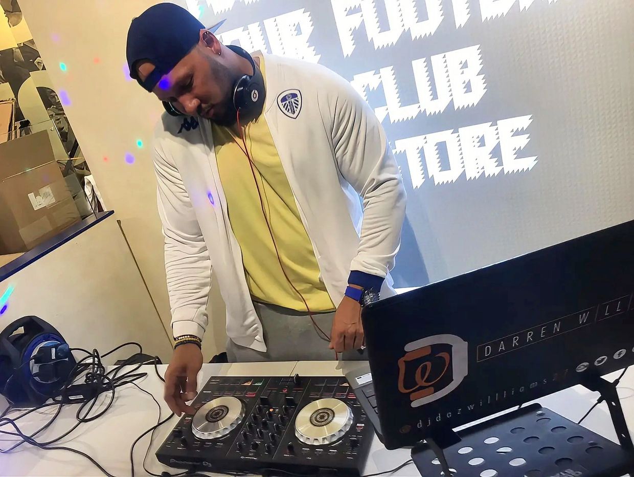 DJ wearing headphones adjusts controls on a mixer at a music event.