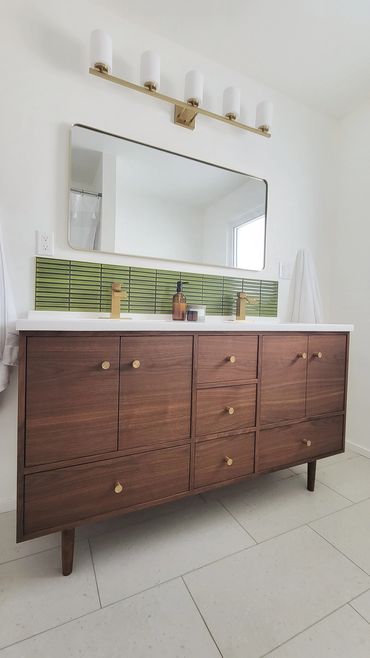 Custom black walnut double vanity midcentury modern style with gold knobs gold fixtures. Green tile
