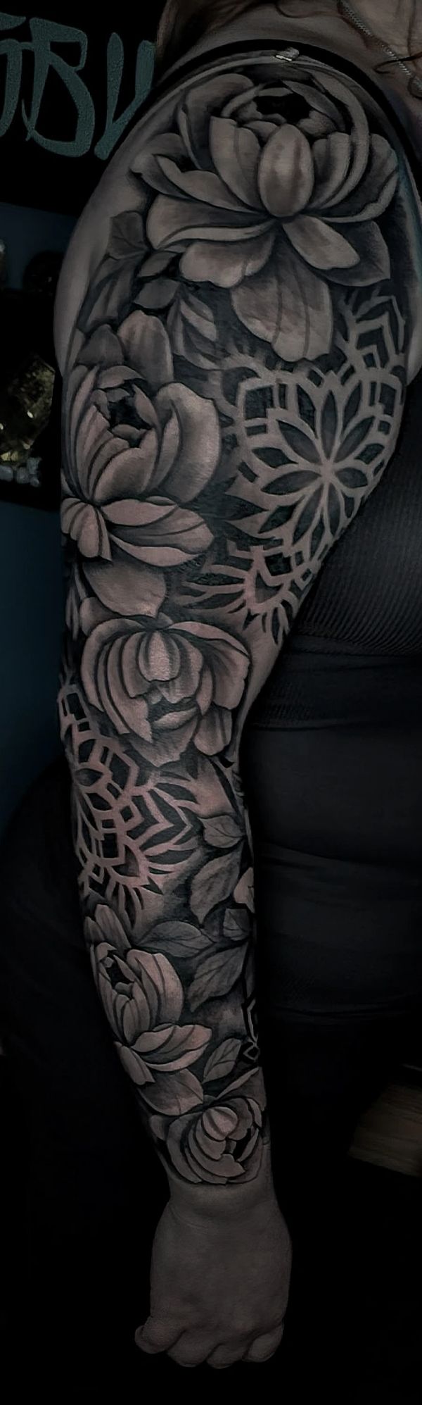 Black and gray floral tattoo sleeve with intricate geometric patterns.