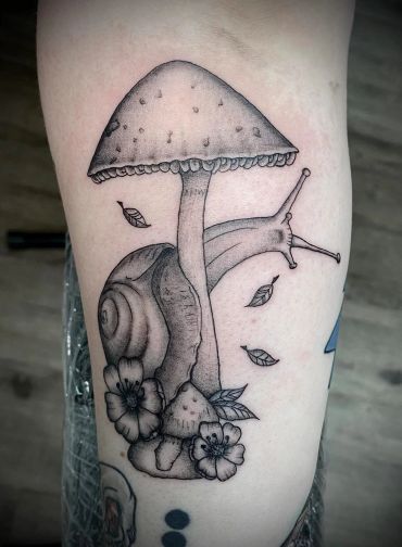 Black and gray tattoo of a snail with a mushroom and flowers.