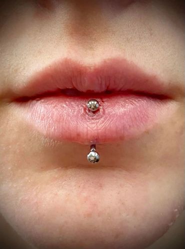 Close-up of lips with a fresh labret piercing.