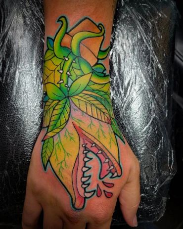 Colorful tattoo of a carnivorous plant with sharp teeth on a hand.