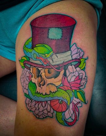 Colorful tattoo of a skull wearing a top hat, entwined with a green snake and surrounded by flowers.