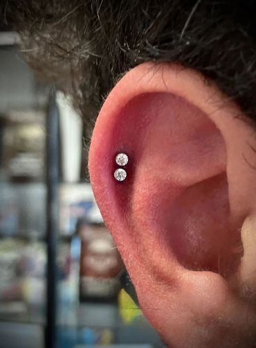 Close-up of an ear with a double piercing adorned with sparkling diamond studs.