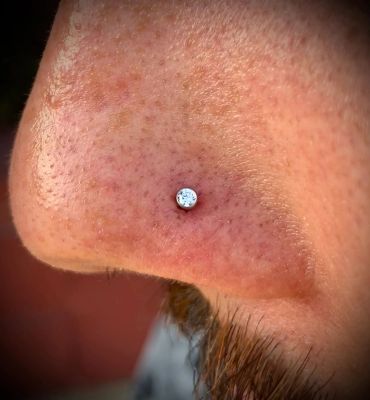 Close-up of a nose with a small, shiny nose stud piercing.