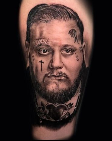 Realistic tattoo portrait of a bearded man with facial tattoos and heart design on neck.