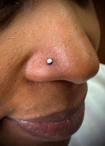 Close-up of a nose with a small opal nose stud piercing.