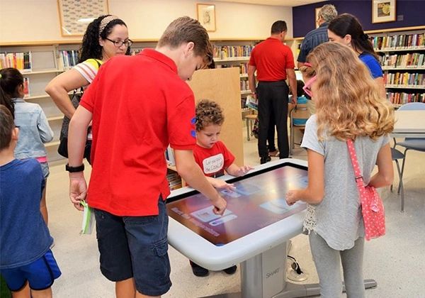 People standing over a digital table.