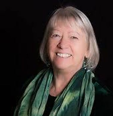 Smiling elderly woman with a green scarf against a black background.