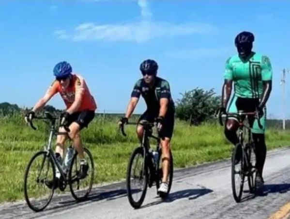 Marcus Allen and two other men cycling on the side of a road.