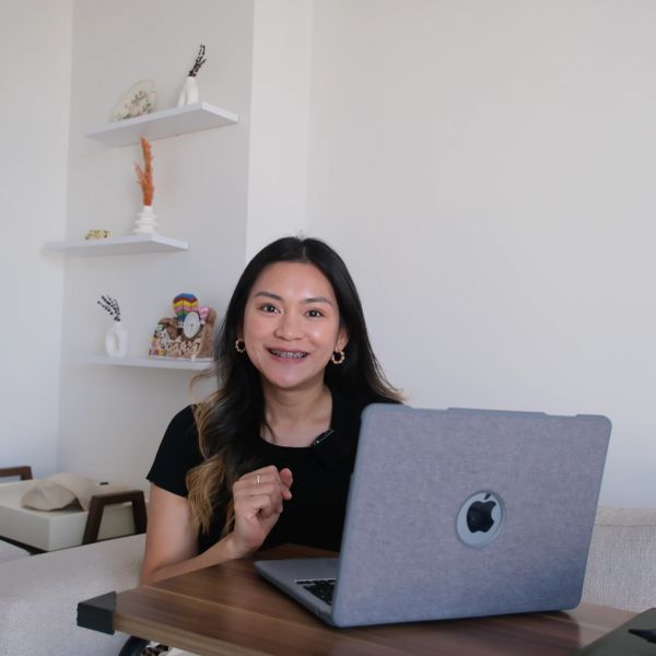 Woman smiling behind a laptop at a table.