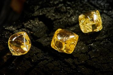 Three yellow gemstones on a dark textured surface.