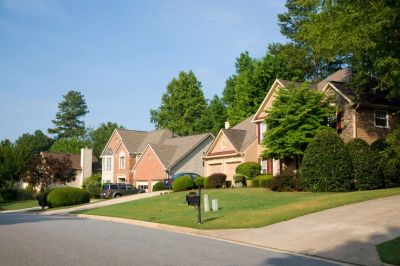 A tree-lined street of brick and siding homes with manicured lawns in Alpharetta, Georgia.