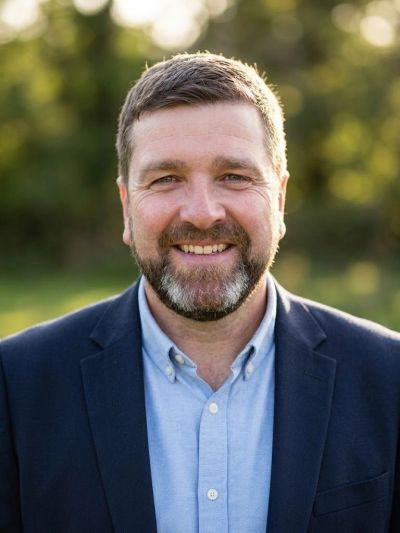 Smiling man in blue blazer outdoors.