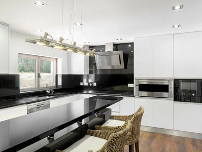 Modern kitchen with black and white design and wicker chairs.