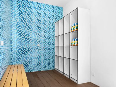 Locker room with blue tiled wall and wooden bench.