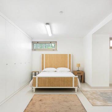 Minimalist bedroom with a wooden bed frame and white walls.
