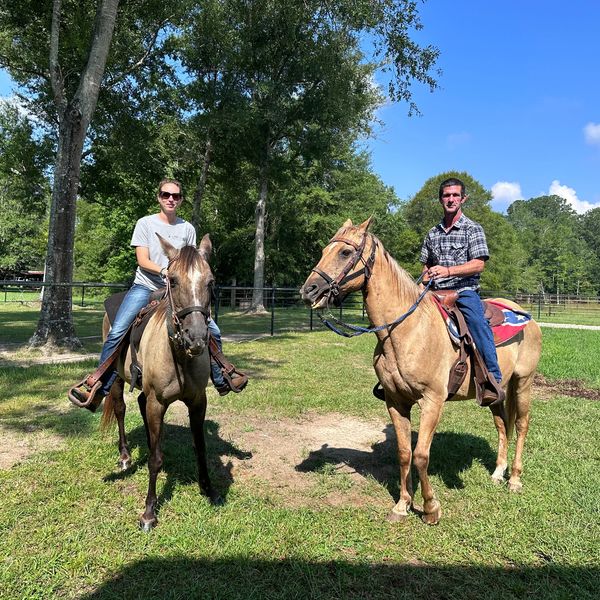 People riding horses in the pasture at Big Hat Ranch.