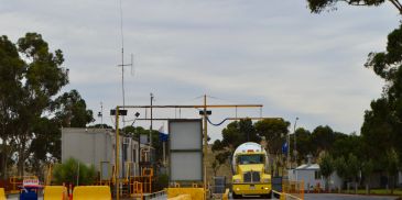 Yellow school bus entering a gated checkpoint.