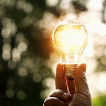 Hand holding a glowing light bulb.
