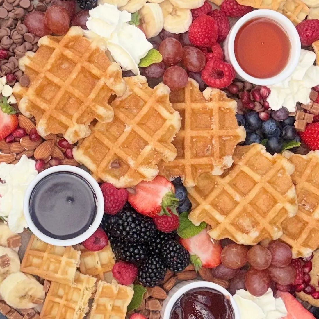 Waffles with assorted berries, dips, and whipped cream.