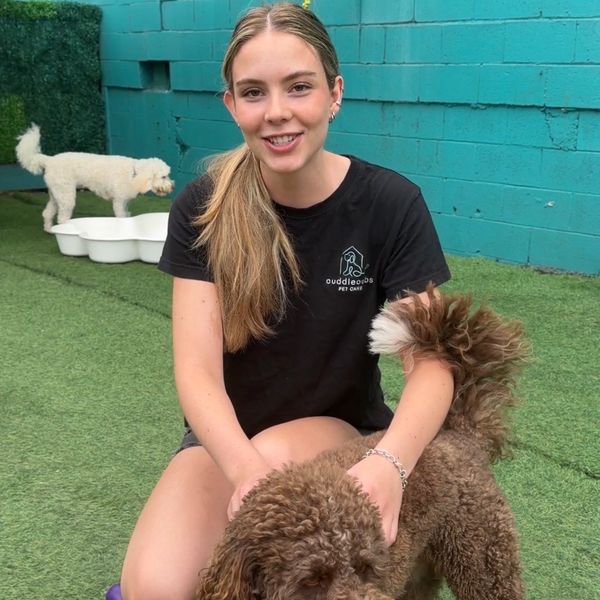 Young woman happily posing with a brown and white dog in a pet care area.