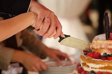 Bride and groom hands cutting a wedding cake