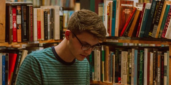 Young man reading a book in a cozy library.